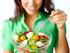 Woman in a green shirt eating a salad
