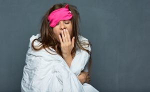 Woman wrapped in a blanket with an eye mask