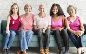 Five women sitting on a couch smiling