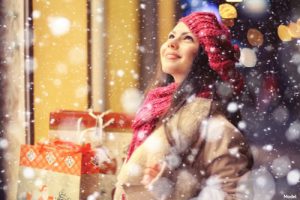 Woman standing in the snow holding gifts