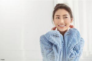 Smiling woman with hair in a bun wearing a blue knit sweater