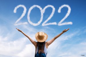Woman in a straw hat looking at "2022" written in sky writing