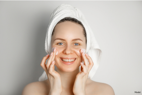 Woman smiling, performing a skin care routine