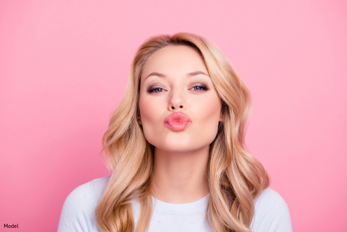 Woman making a kissing face, pink background