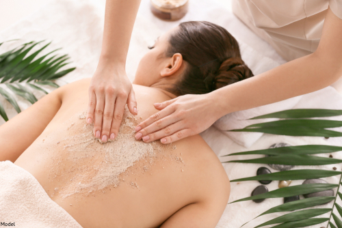 Woman receiving an exfoliating scrub on her back at a spa