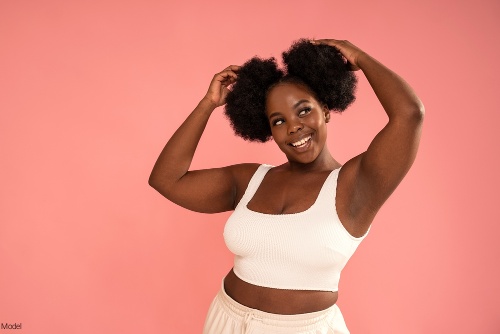 Confident woman in activewear smiling and touching her hair which is in two buns