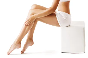 a portrait of a woman sitting on a chair showing off smooth skin and legs after laser hair removal treatments